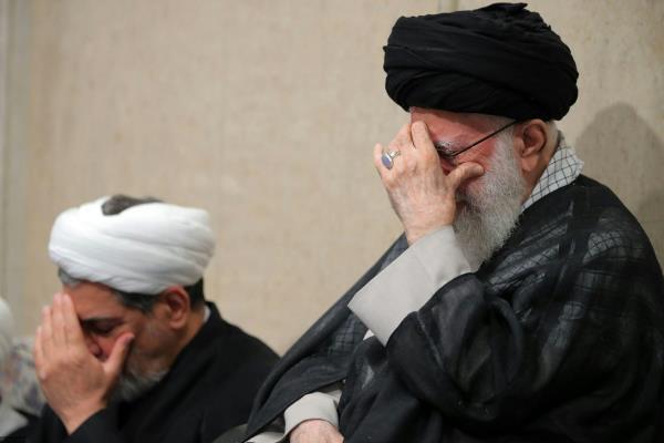 Iran's supreme leader Ali Khamenei holds his head in his hand.