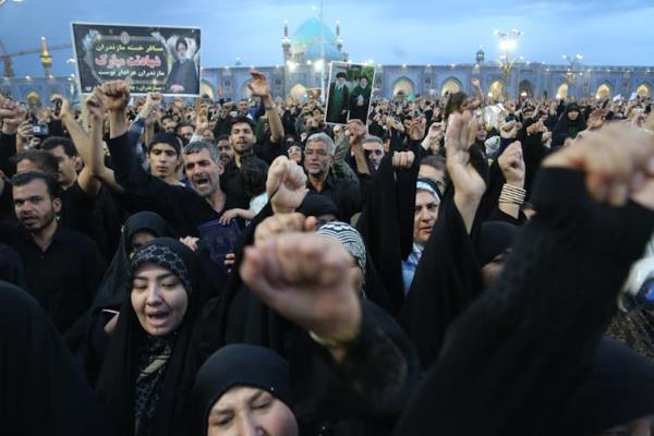 A large crowd of Iranians holding up pictures of the dead former president Ebrahim Raisi.